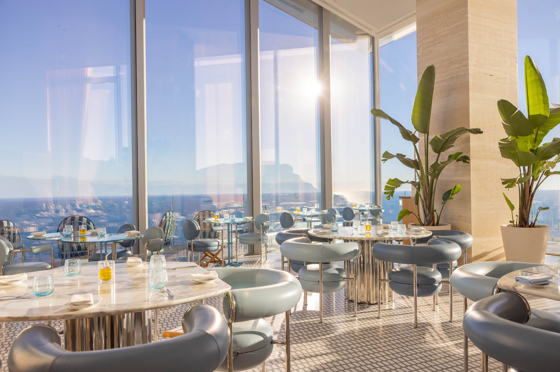 Table mise en place avec salle de restaurant et vue sur la mer en arrière plan