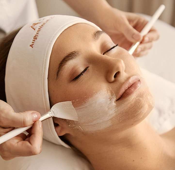 Woman having Augustinus Bader treatment with brushes and cream, wearing a Augustinus Bader headband