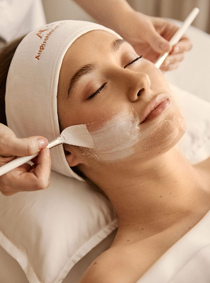 Woman having Augustinus Bader treatment with brushes and cream, wearing a Augustinus Bader headband